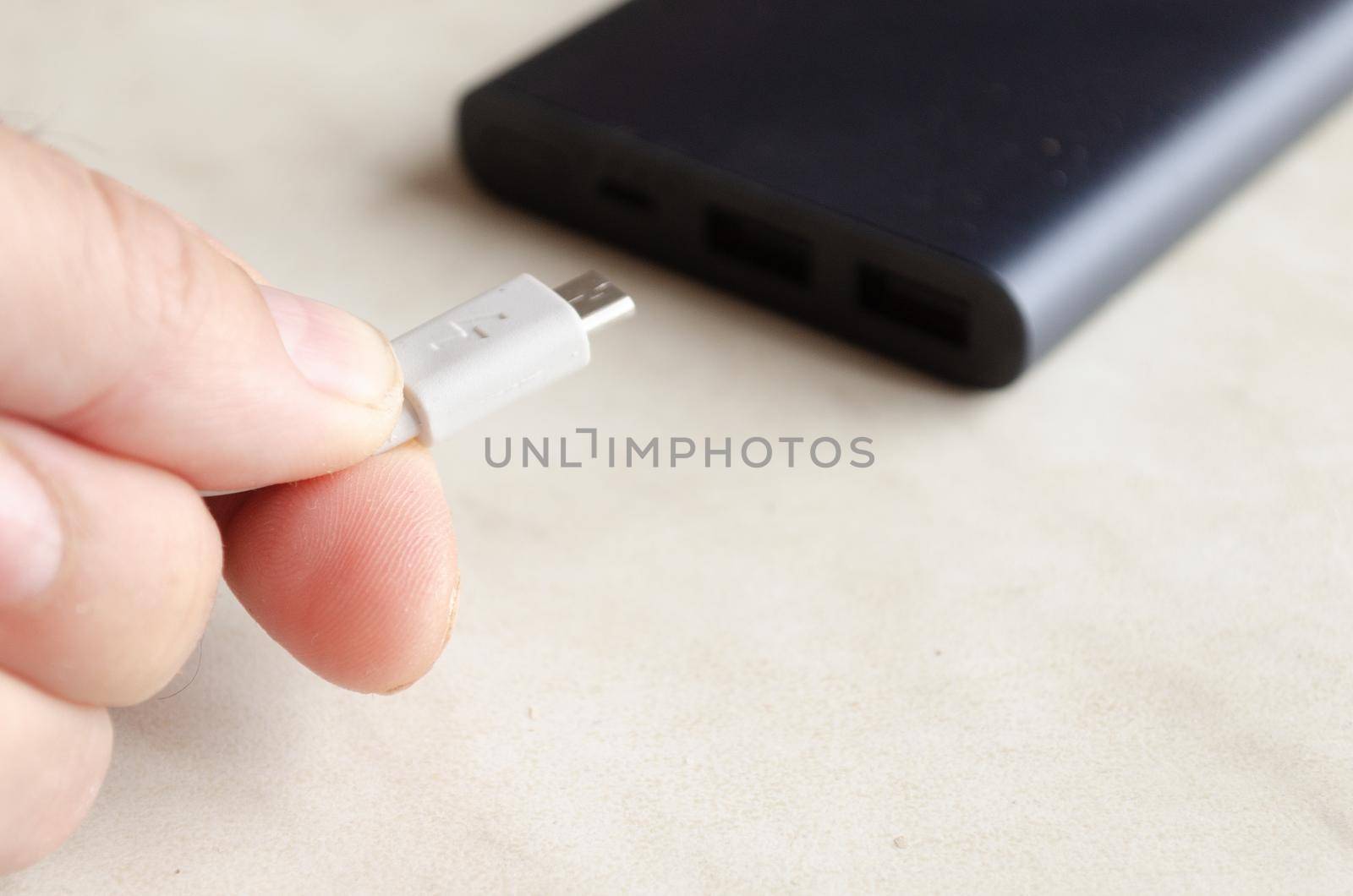 a man holds a charging cable for charging a powerbank.