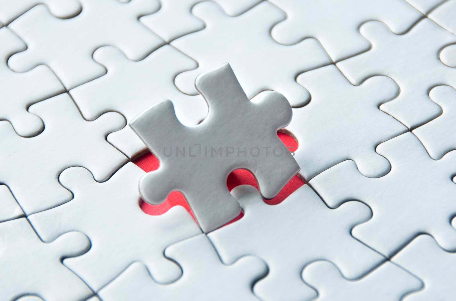 White jigsaw puzzle on red cover background with customizable space for text. Copy space and puzzle concept