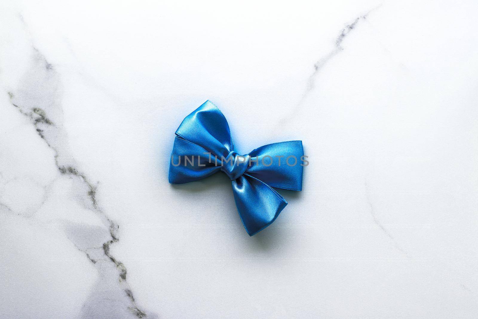 Happy holidays, festive decoration and brand sale promotion concept - Blue silk ribbon and bow on luxury marble background, holiday flatlay backdrop