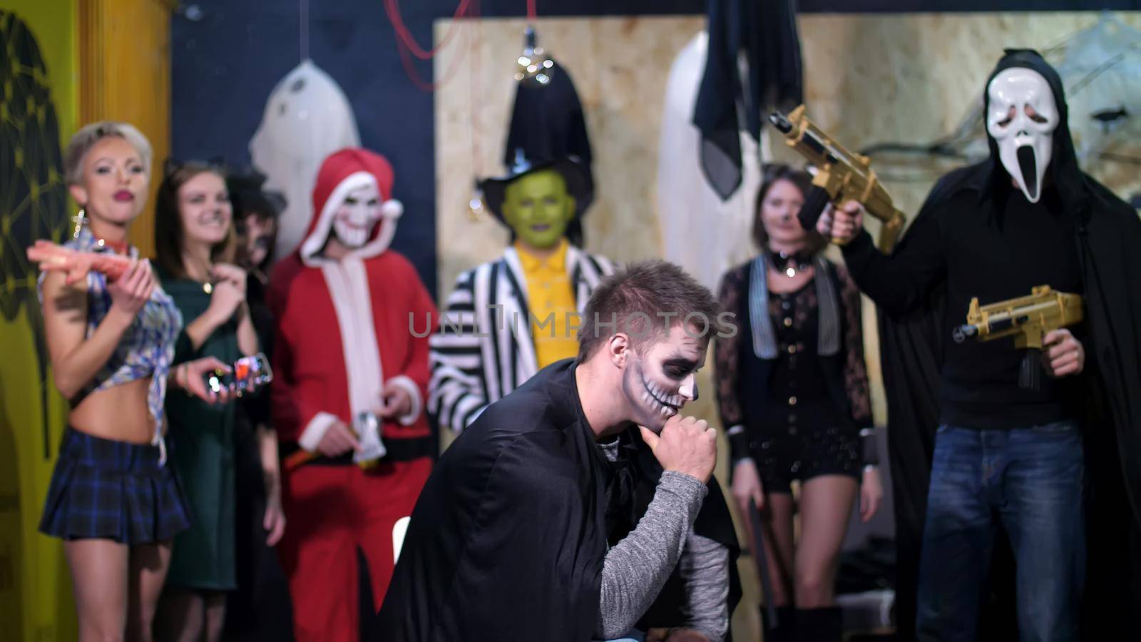 Halloween party, photo session, young people dressed up in scary costumes and made a horrific make-up. they are having fun, in the background Halloween scenery is seen. High quality photo