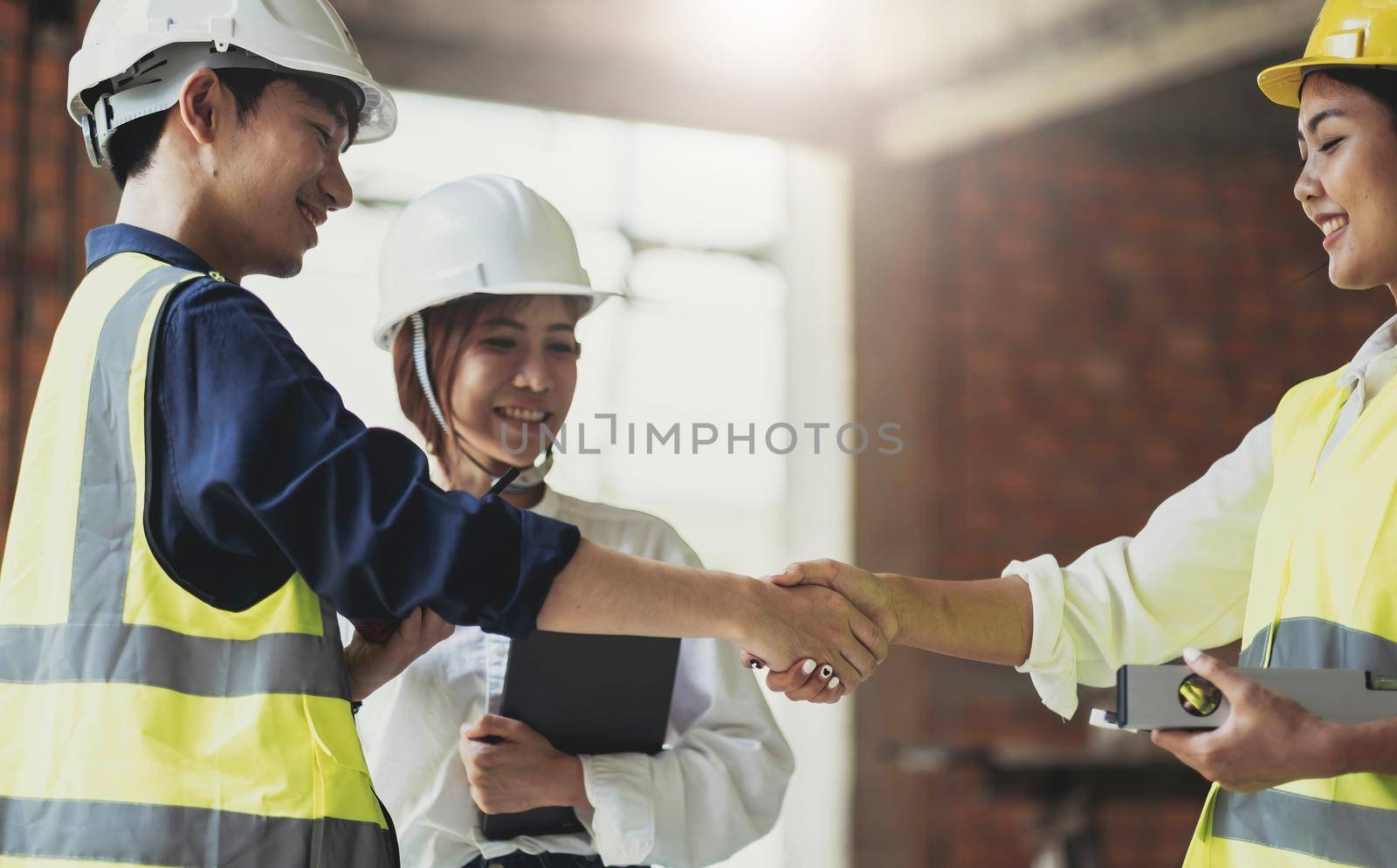 Male civil engineer or architect hand shake with contractor after discussing about designing of building styles and inspect progress of housing project at construction sites. Worker work in real estate