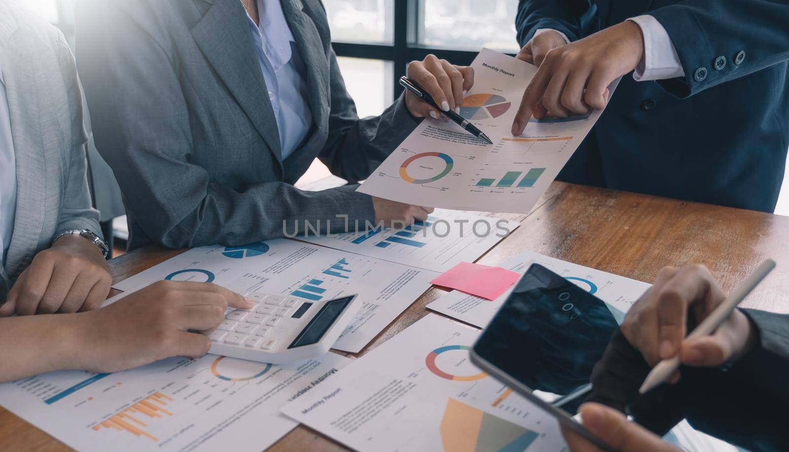 businessmen and woman sitting, working and discussing questions at meeting in modern office, close-up by wichayada