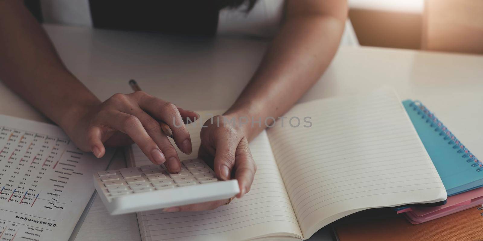 Close-up of business woman hands using a calculator to check company finances and earnings and budget. by wichayada