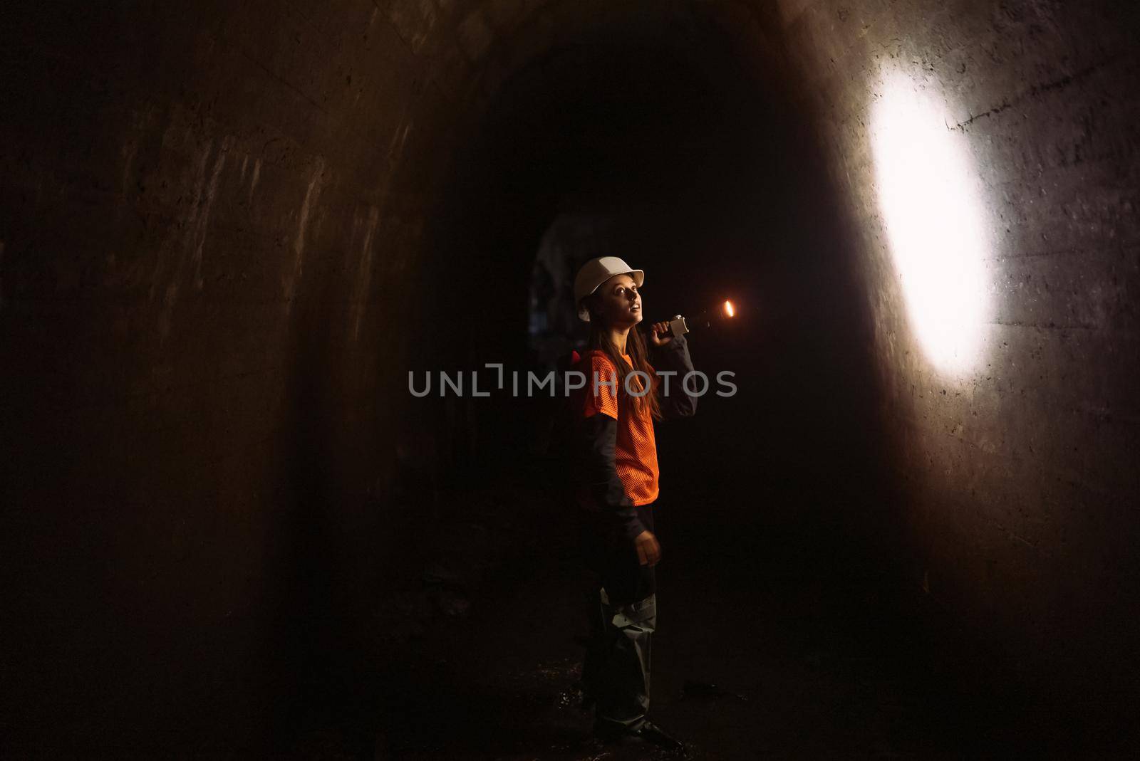 A young female digger with a flashlight explores the tunnel