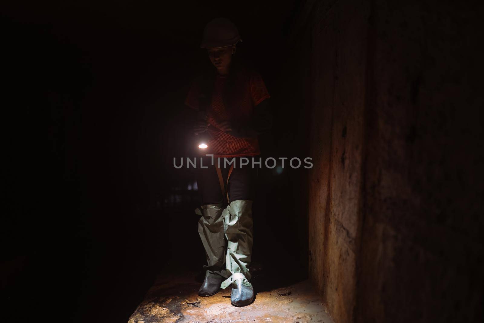 A young female digger with a flashlight explores the tunnel