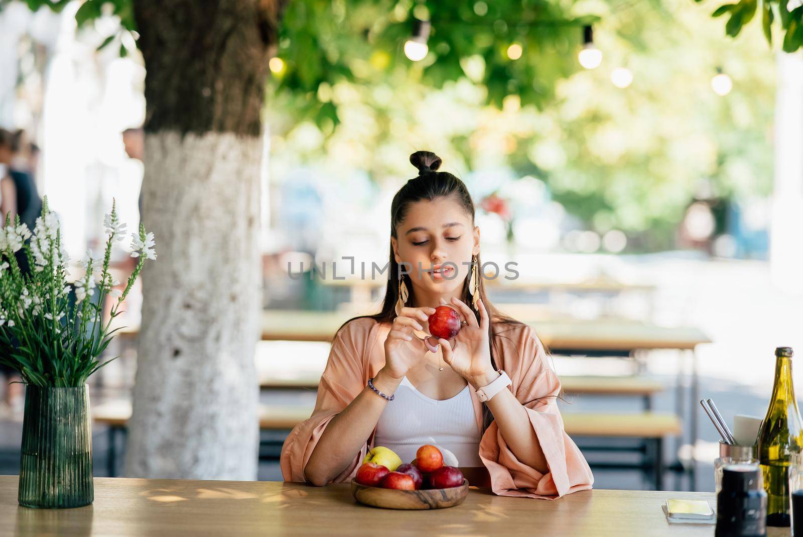 Young beautiful smiling hipster woman sitting in veranda cafe in street.