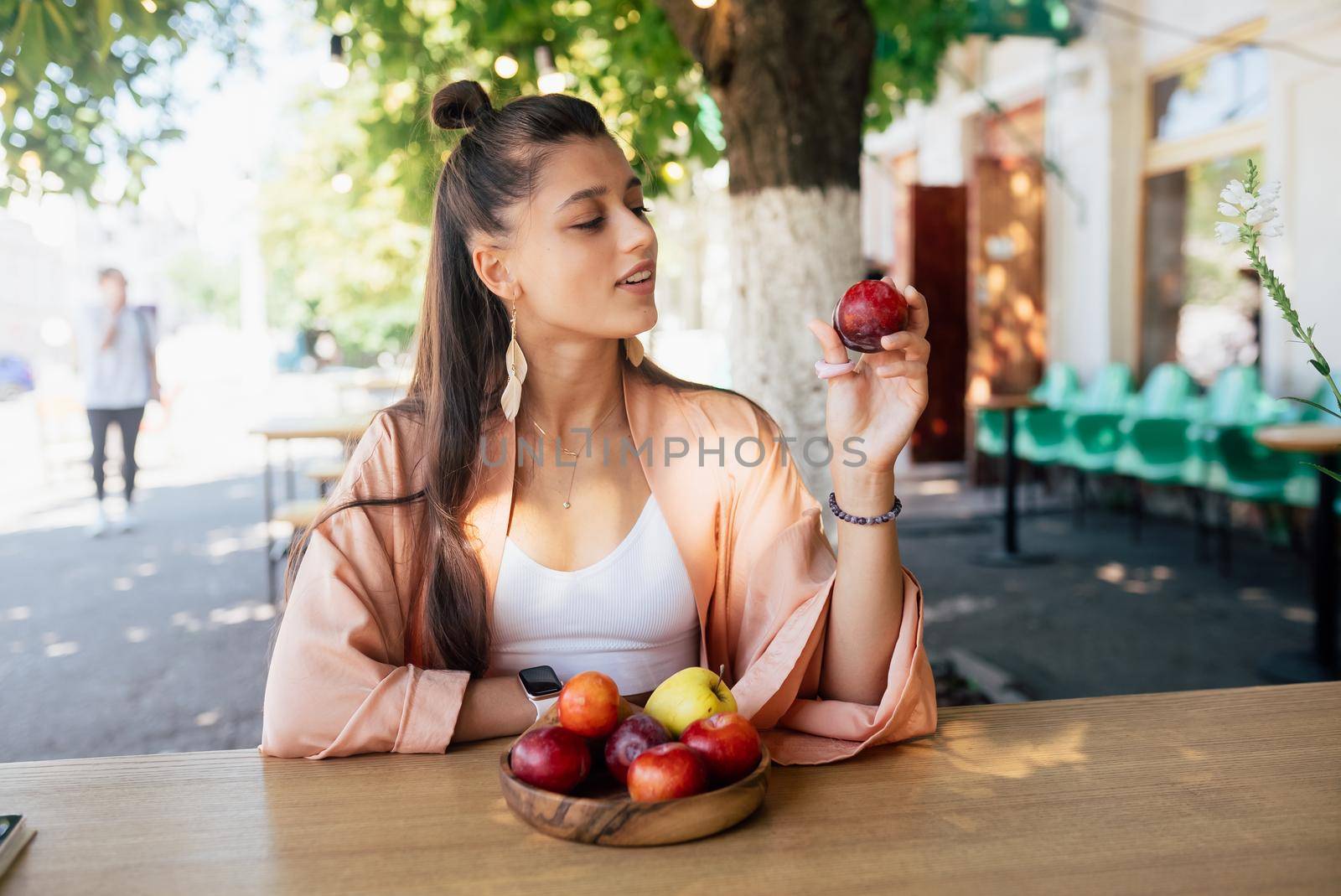 Young beautiful smiling hipster woman sitting in veranda cafe in street.