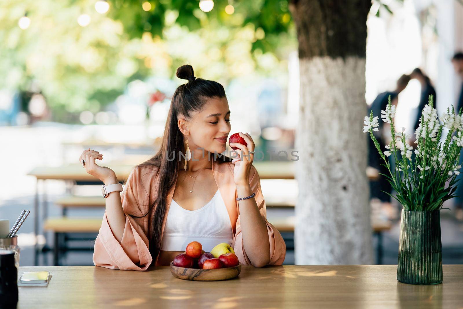 Young beautiful smiling hipster woman sitting in veranda cafe in street.