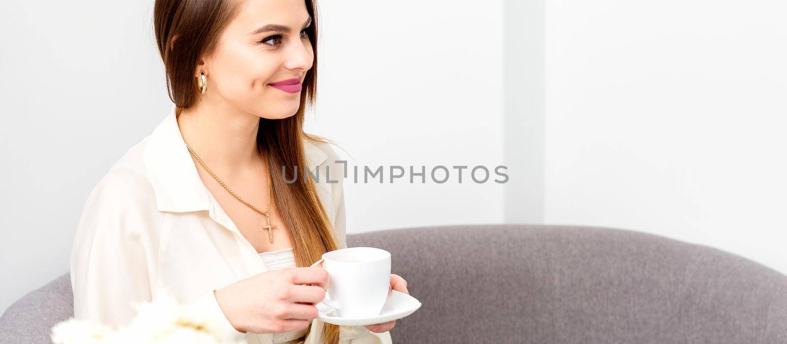 Female caucasian client with a cup of coffee in his hands smiling at a doctor's appointment