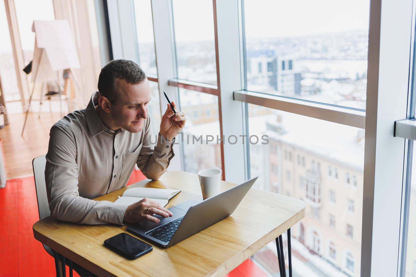 Smart young man looking for information on a website and working as a freelancer on developing a graphic project on a modern laptop using a wireless internet connection in a cafe interior