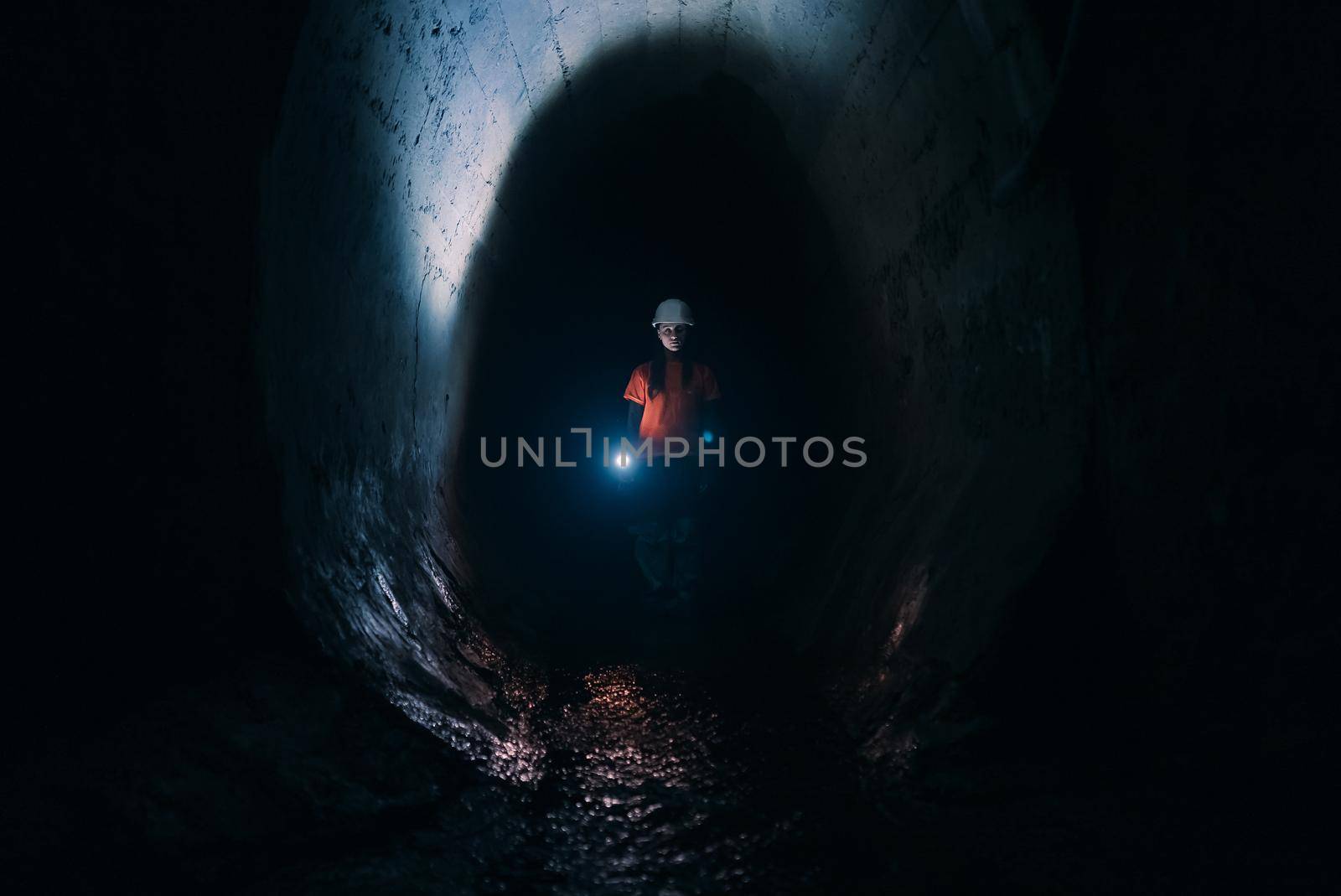 A young female digger with a flashlight explores the tunnel