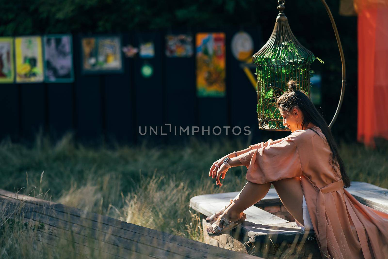 Side view of pleased brunette woman sitting on bench and enjoying the sunset