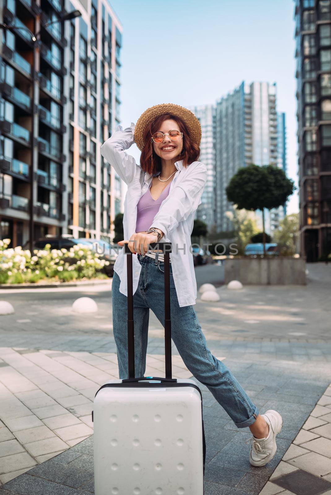 Stylish woman with suitcase looking at camera at the street