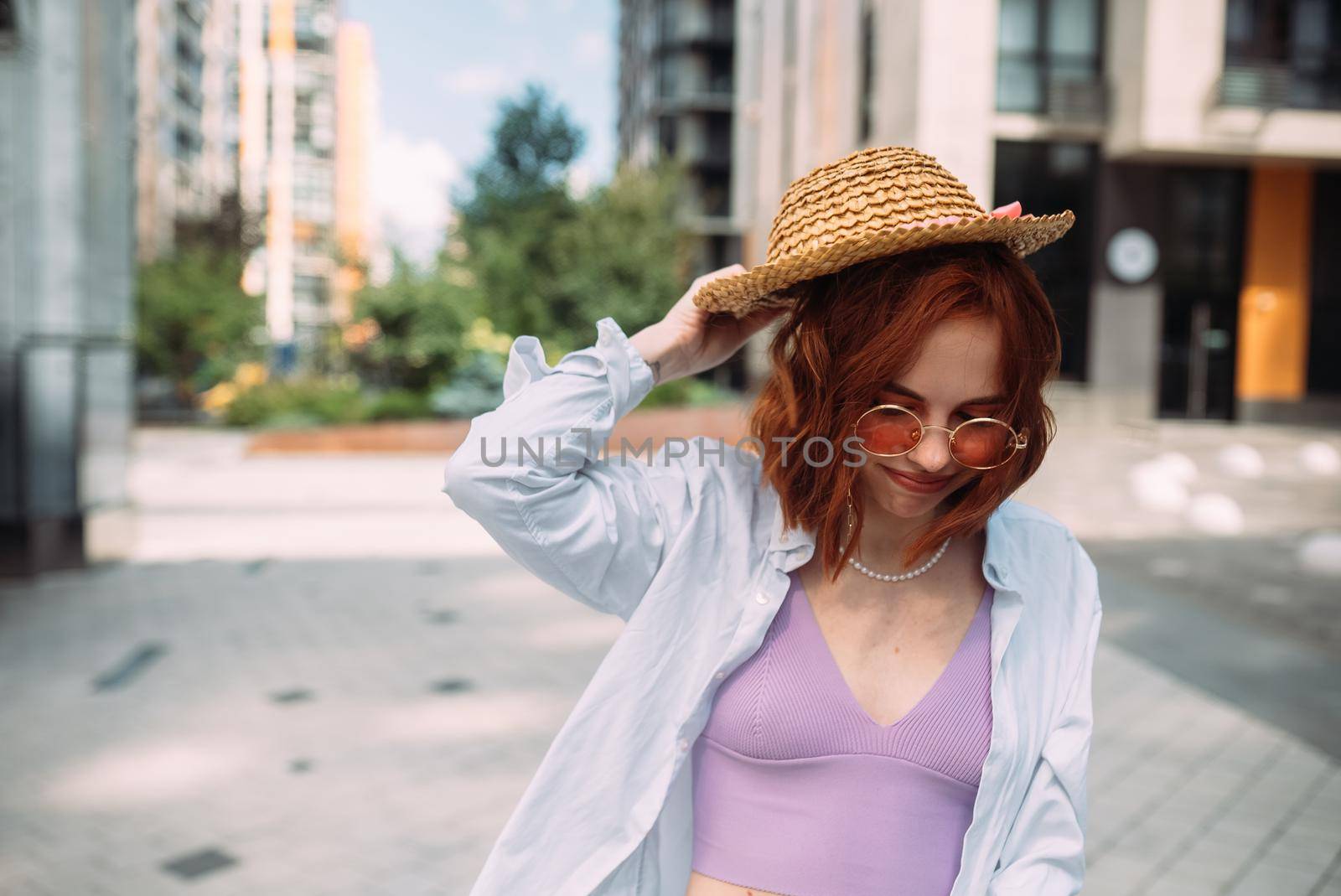 A red-haired woman poses for the camera on the street