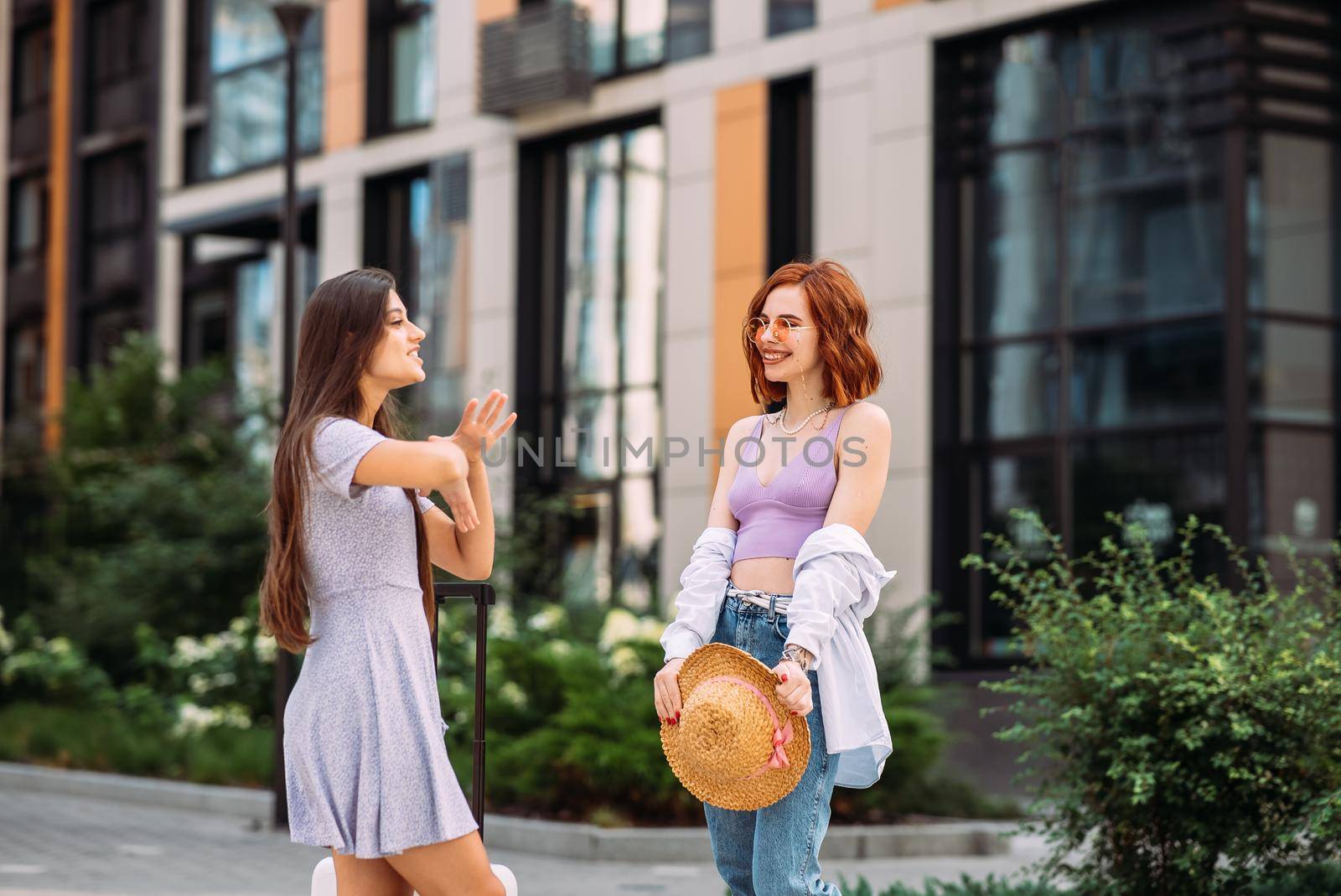 Friendly talk. Side view of two beautiful young women talking and standing outdoors