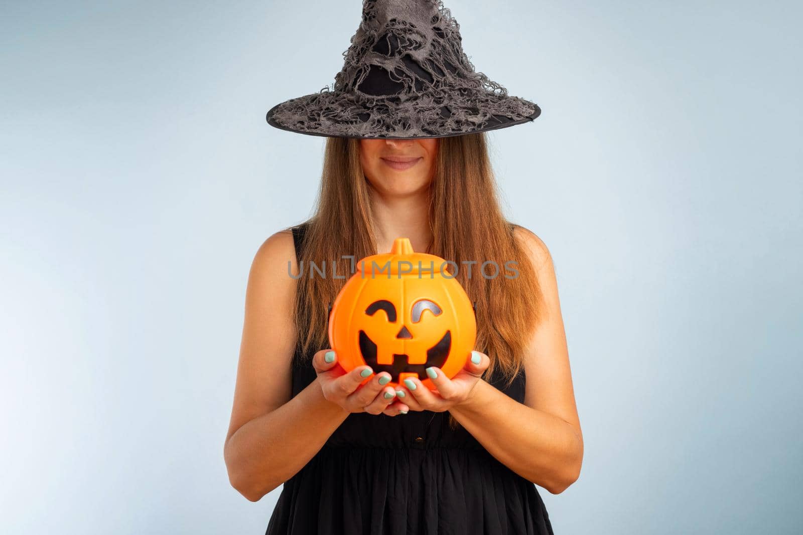 Happy young woman in halloween witch costume with pumpkin basket by andreyz