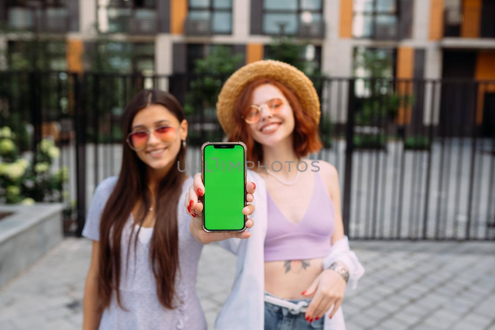 Two lovely girlfriends shows their phone to the camera