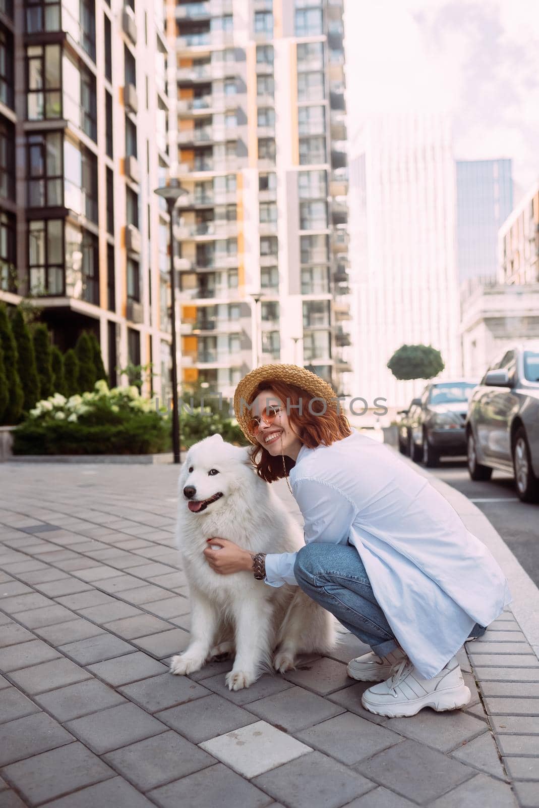 A young woman hugs a big dog at sunset in summer