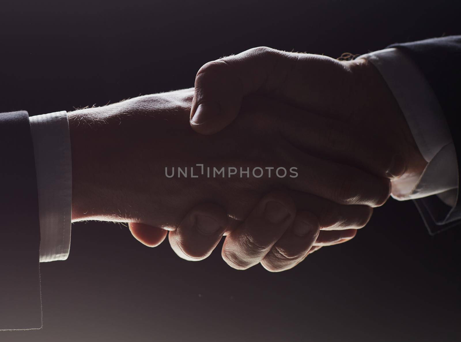 Photo of two men shaking hands on a black background