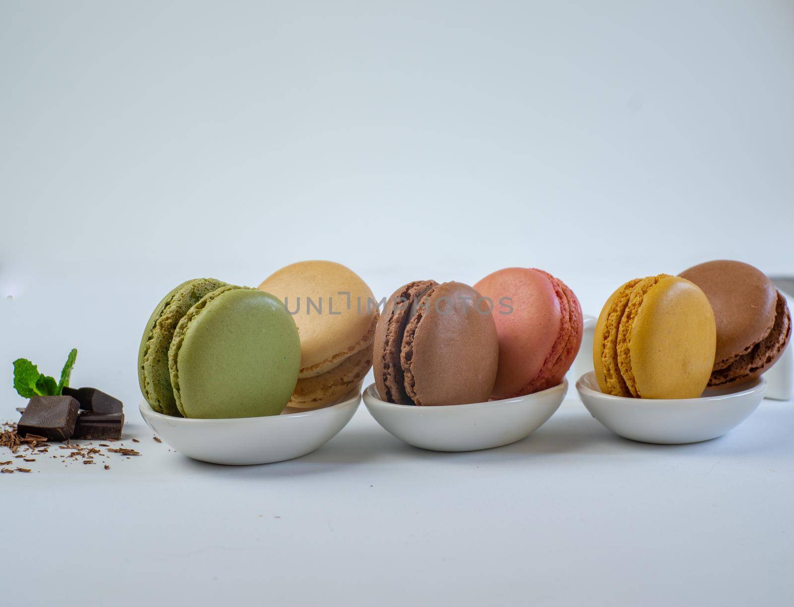 colorful macarons on white background with cup of coffee