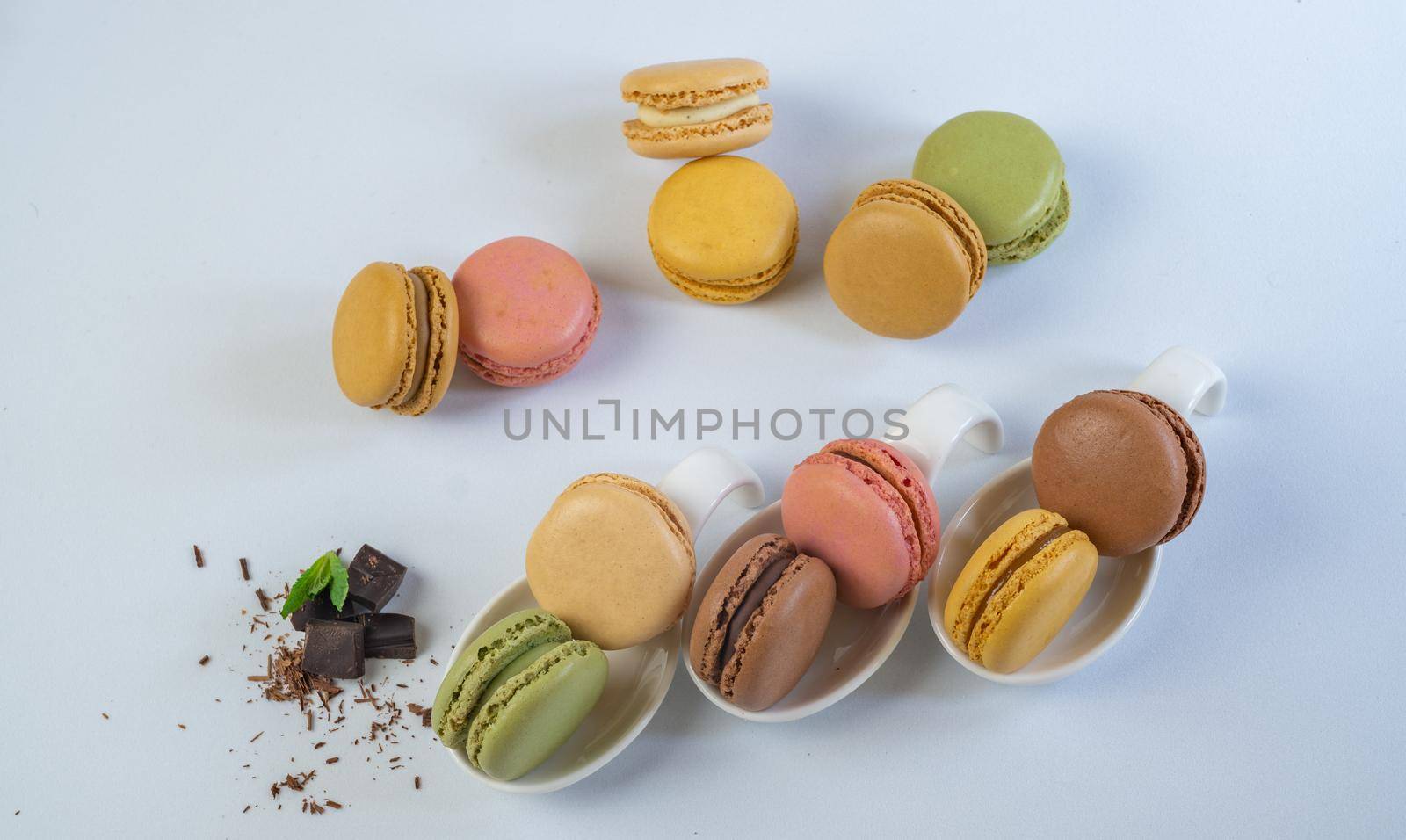 colorful macarons on white background with cup of coffee