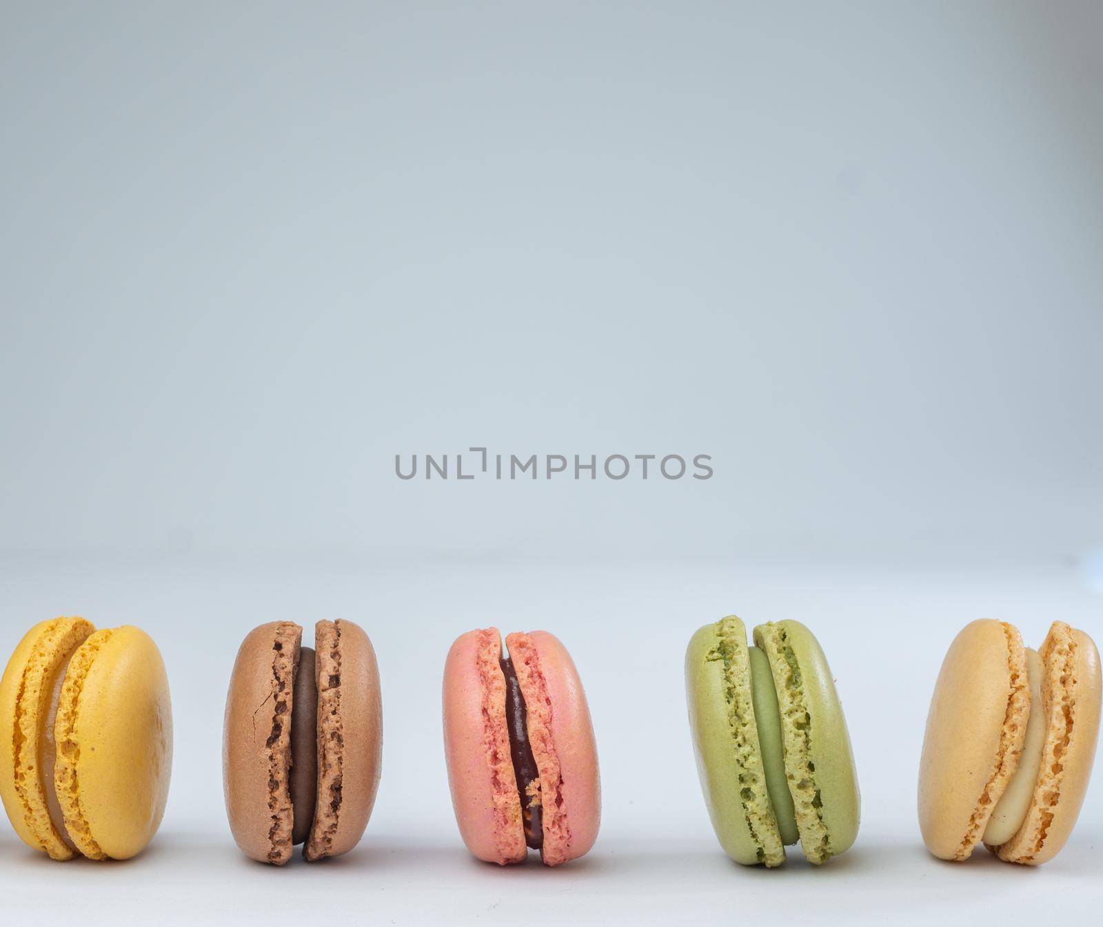 colorful macarons on white background with cup of coffee