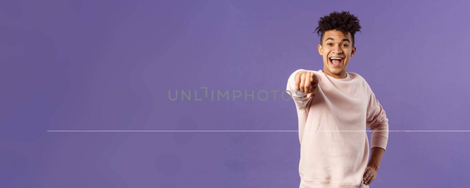 Portrait of outgoing happy hispanic male student making his choice, laughing over something extremely funny point finger at camera with amused smile, standing purple background.