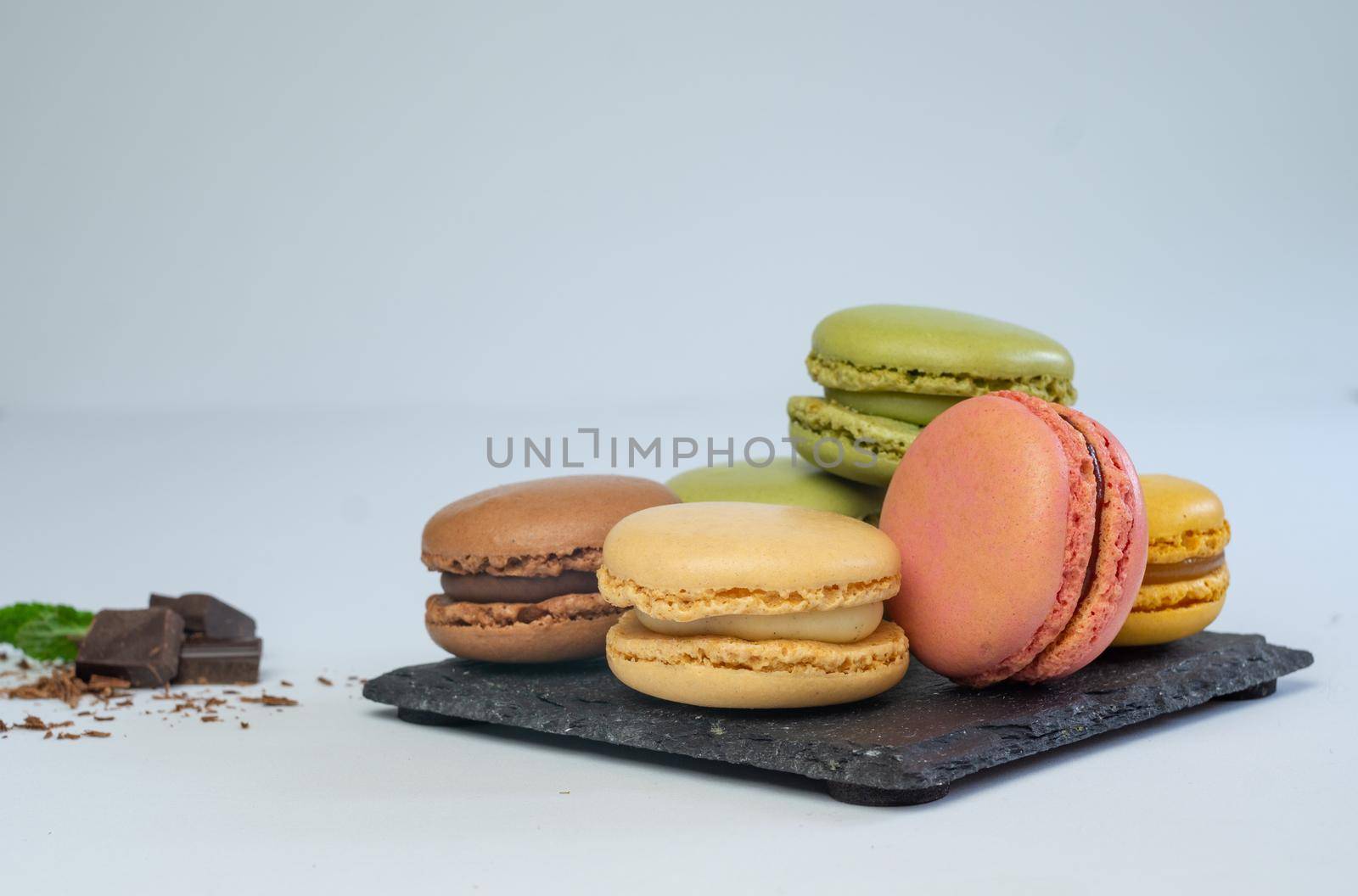 colorful macarons on white background with cup of coffee