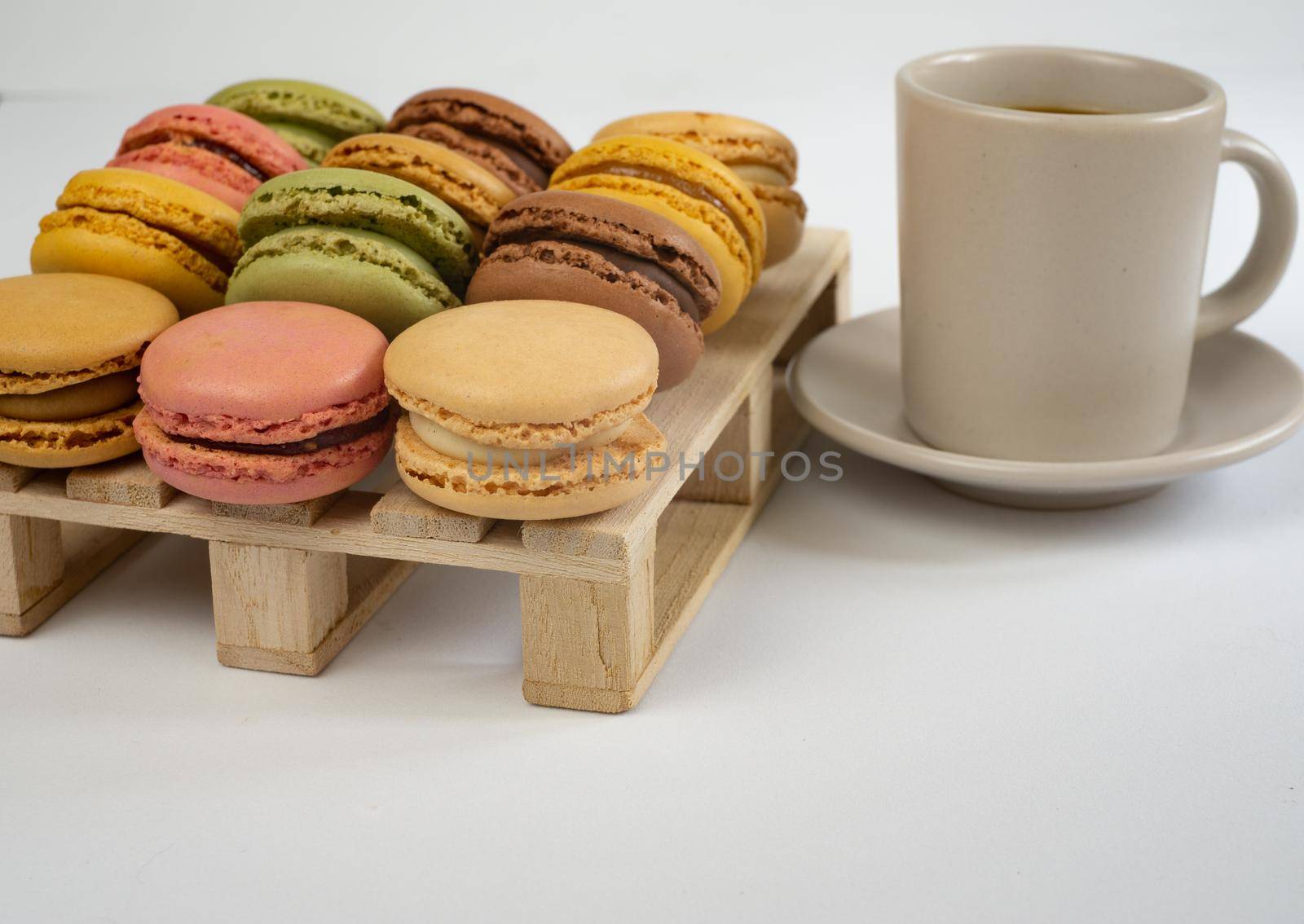 colorful macarons on white background with cup of coffee