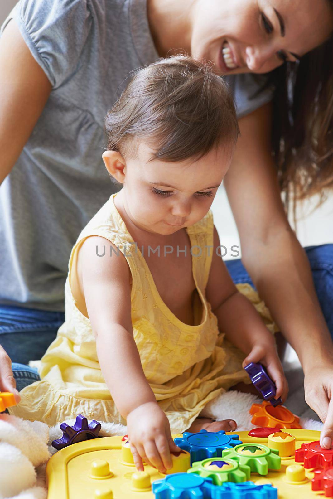 Shes such a clever little girl. an adorable baby girl sitting on the floor with her mom and playing with toys. by YuriArcurs