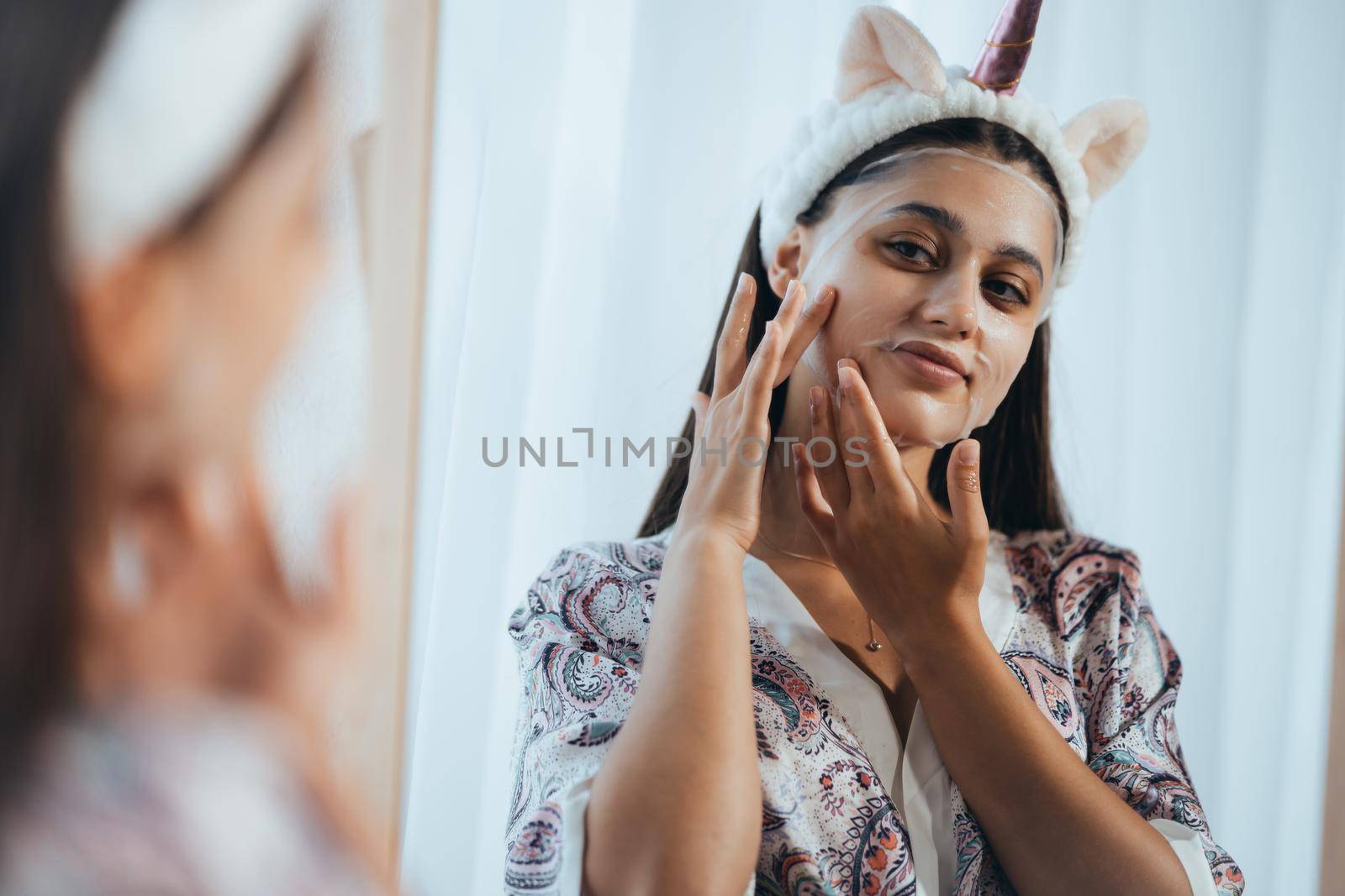 Young model applying cosmetic cream treatment on her face