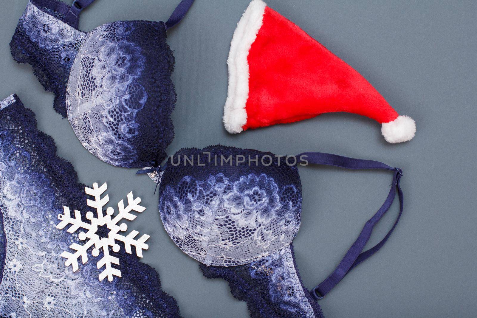 Beautiful, blue lace bra and panties with Santa's hat and snowflacke on gray background. Women sexy underwear set. Romantic lingerie for temptation. Christmas day concept.