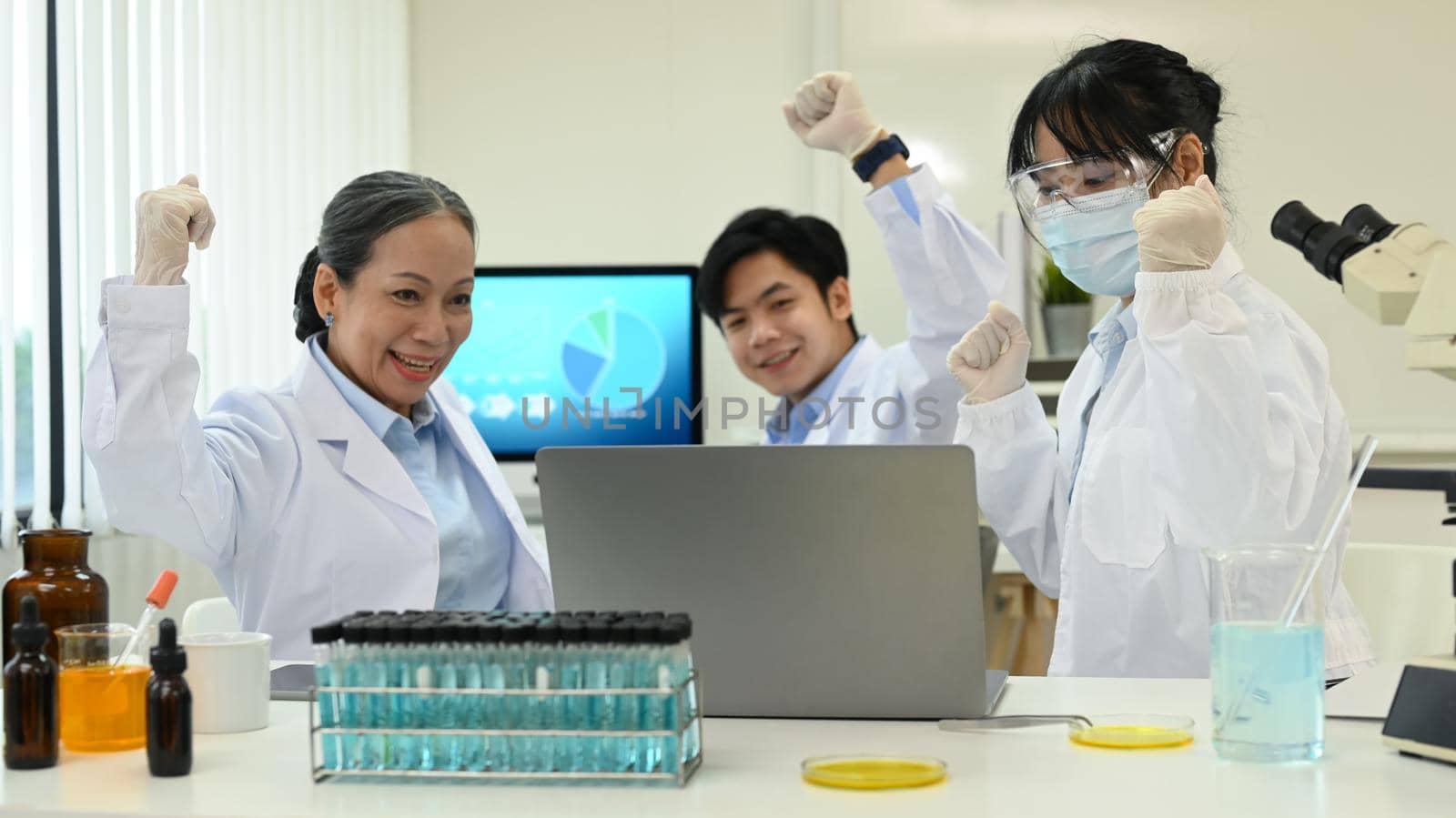 Group of happy scientists celebrating success results of the experiment, makes an important discovery in research laboratory.