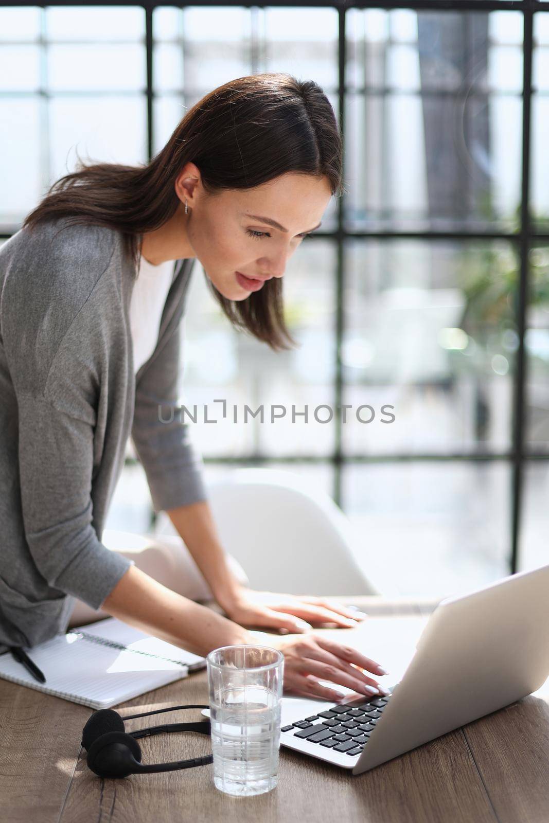 Young business woman standing in her home office writing notes.