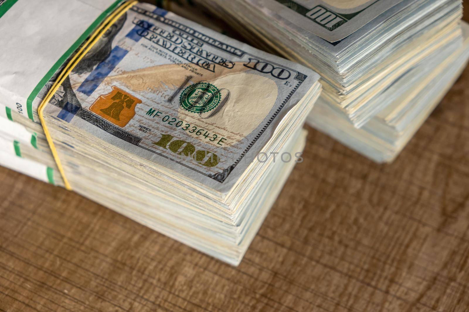 Bundles of 100k US dollars standing on wooden table. selective focus