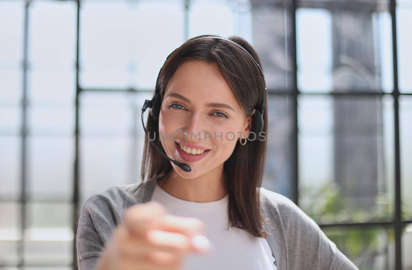 Smiling support phone woman operator in office. pointing at you
