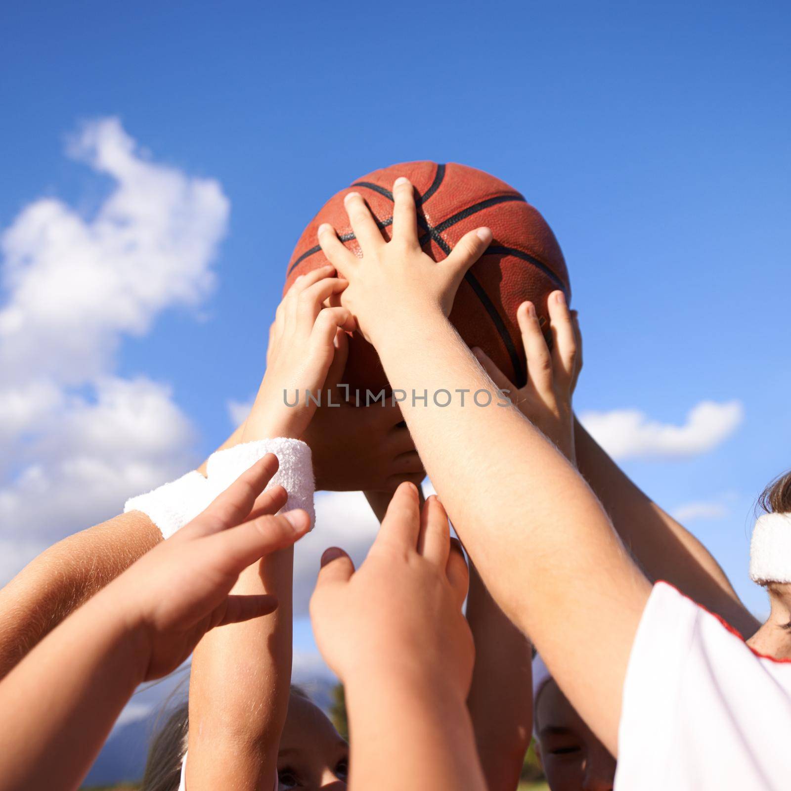 Hands in. A group of basketball players hands holding a basketball together