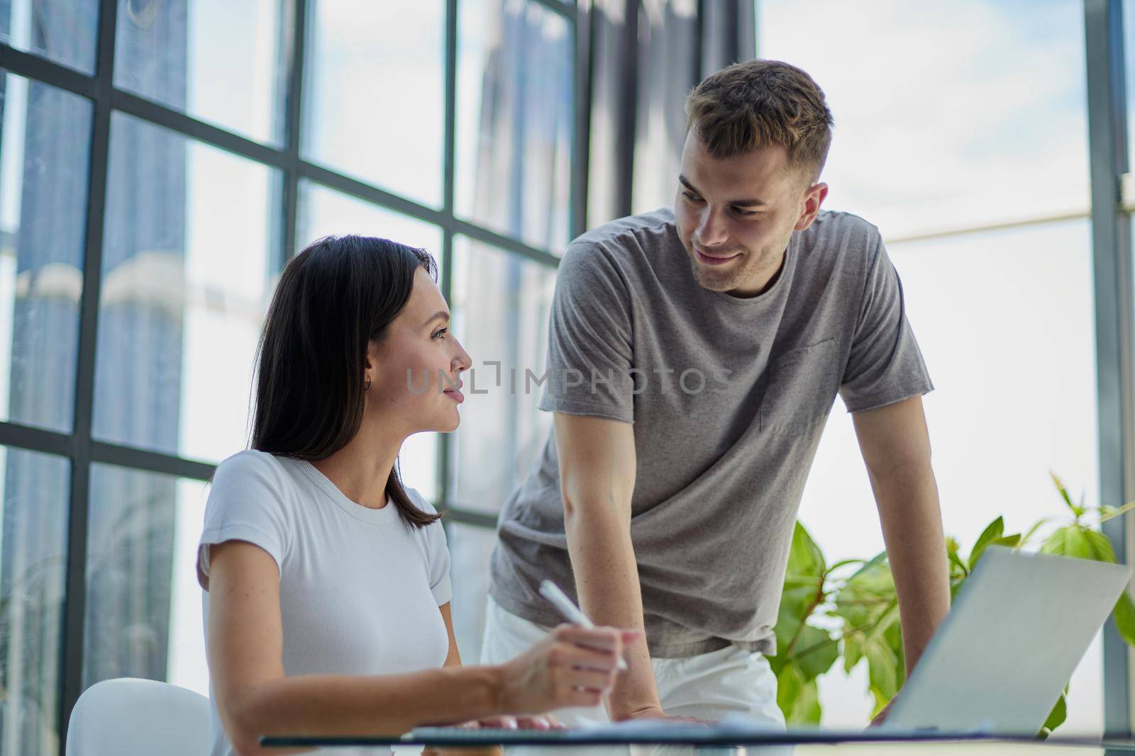 male ceo executive manager mentor giving consultation on financial operations to female colleague intern using laptop sitting in modern office