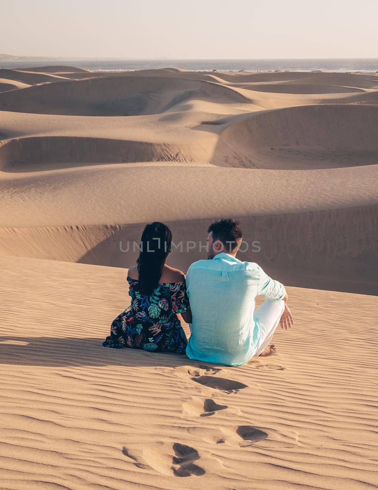 A couple walking at the beach of Maspalomas Gran Canaria Spain, men and woman at the sand dunes desert of Maspalomas Gran Canaria during vacation in Spain