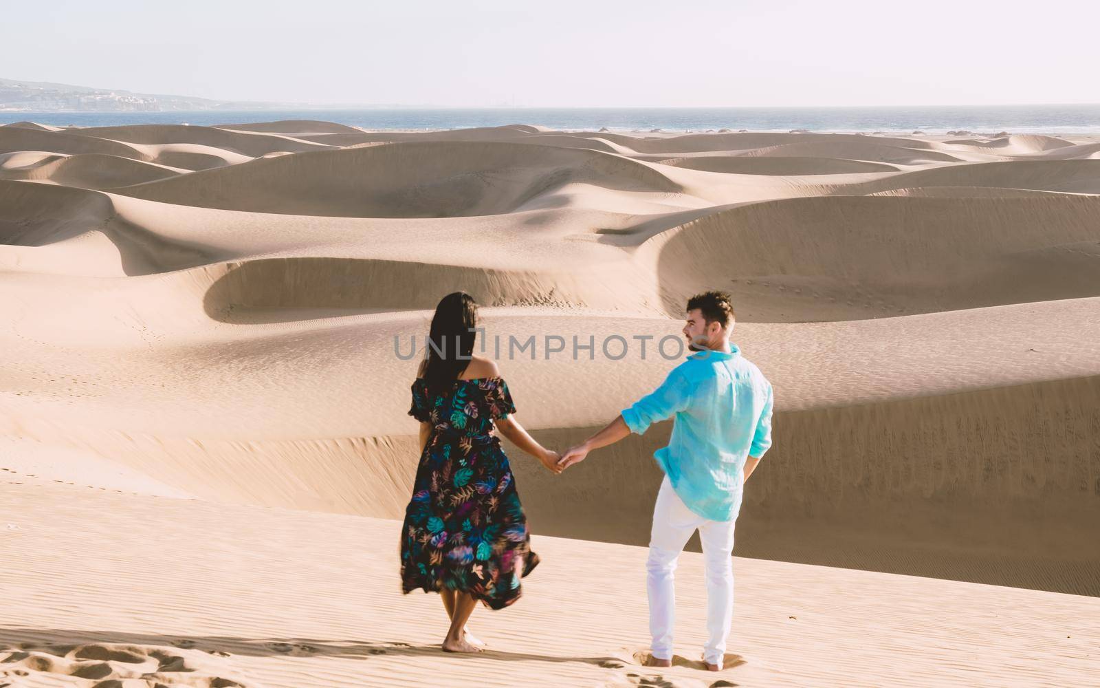 A couple walking at the beach of Maspalomas Gran Canaria Spain, men and woman at the sand dunes desert of Maspalomas Gran Canaria during vacation in Spain