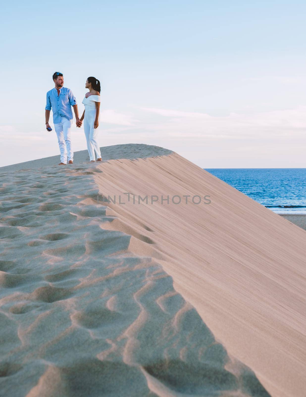 couple walking at the beach of Maspalomas Gran Canaria Spain, men and woman at the sand dunes desert of Maspalomas Gran Canaria