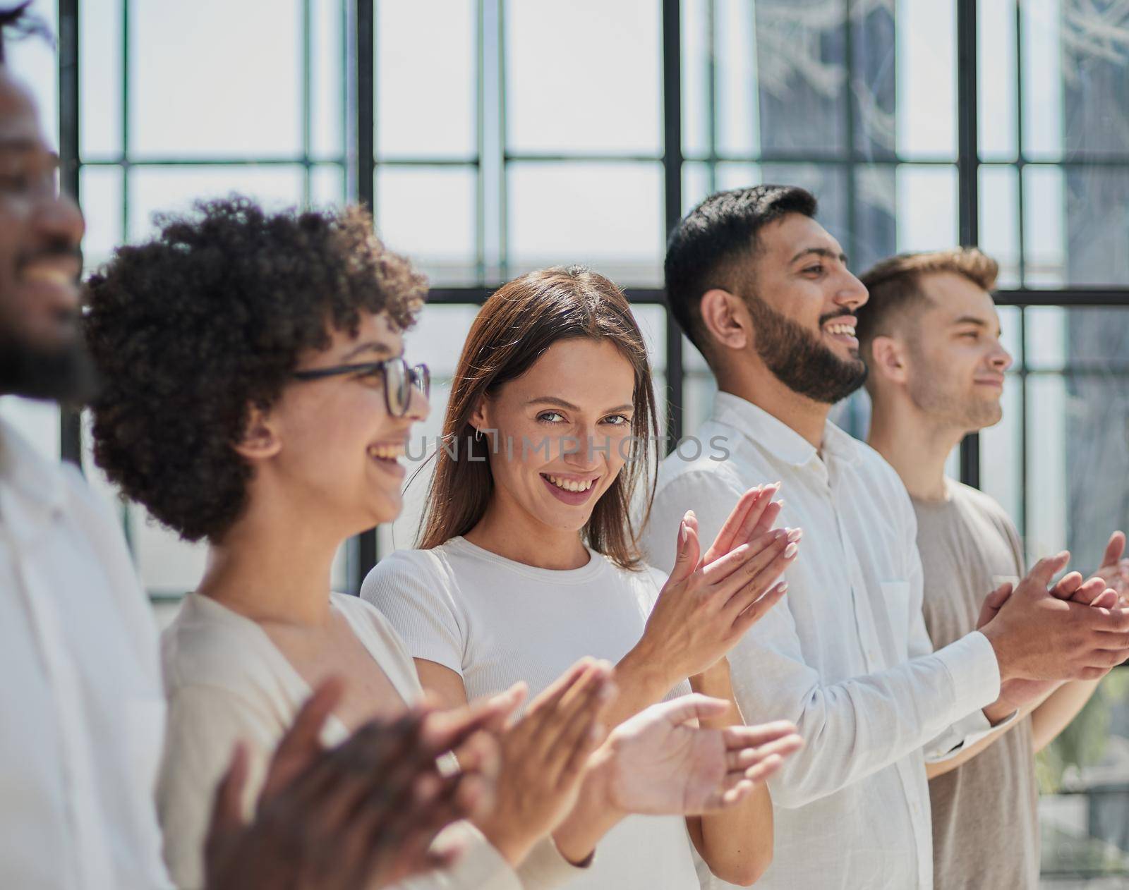 Group of businesspeople sitting in a line and applauding. by Prosto