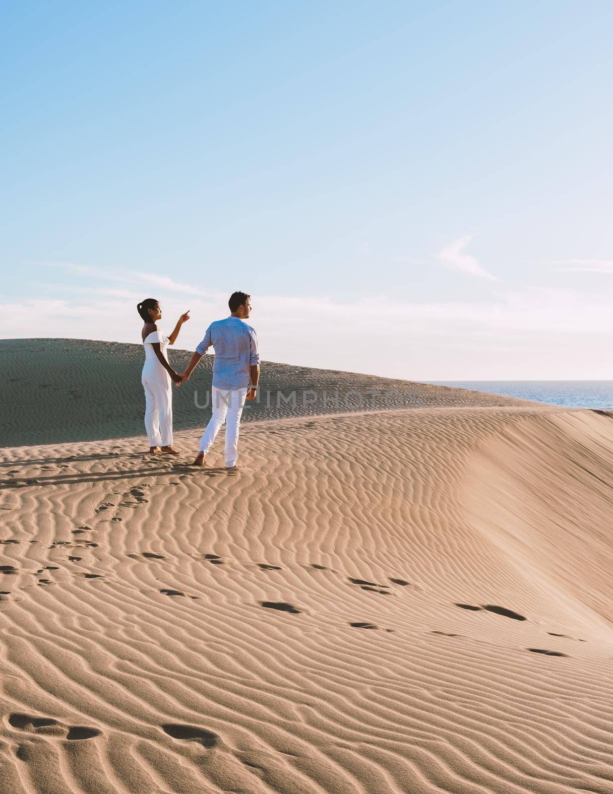 couple walking at the beach of Maspalomas Gran Canaria Spain, men and woman at the sand dunes desert of Maspalomas Gran Canaria
