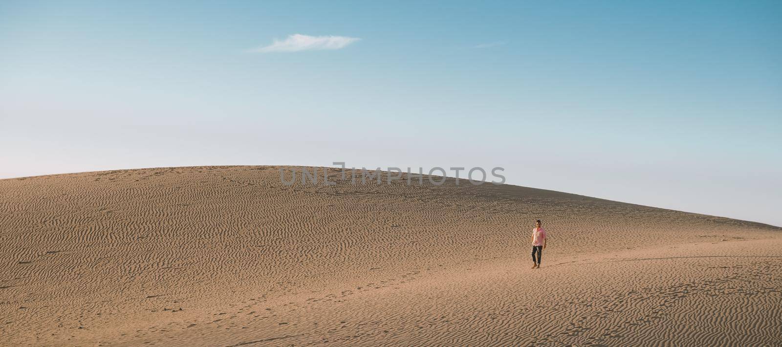 Young men walking at the beach of Maspalomas Gran Canaria Spain, men at the sand dunes desert by fokkebok