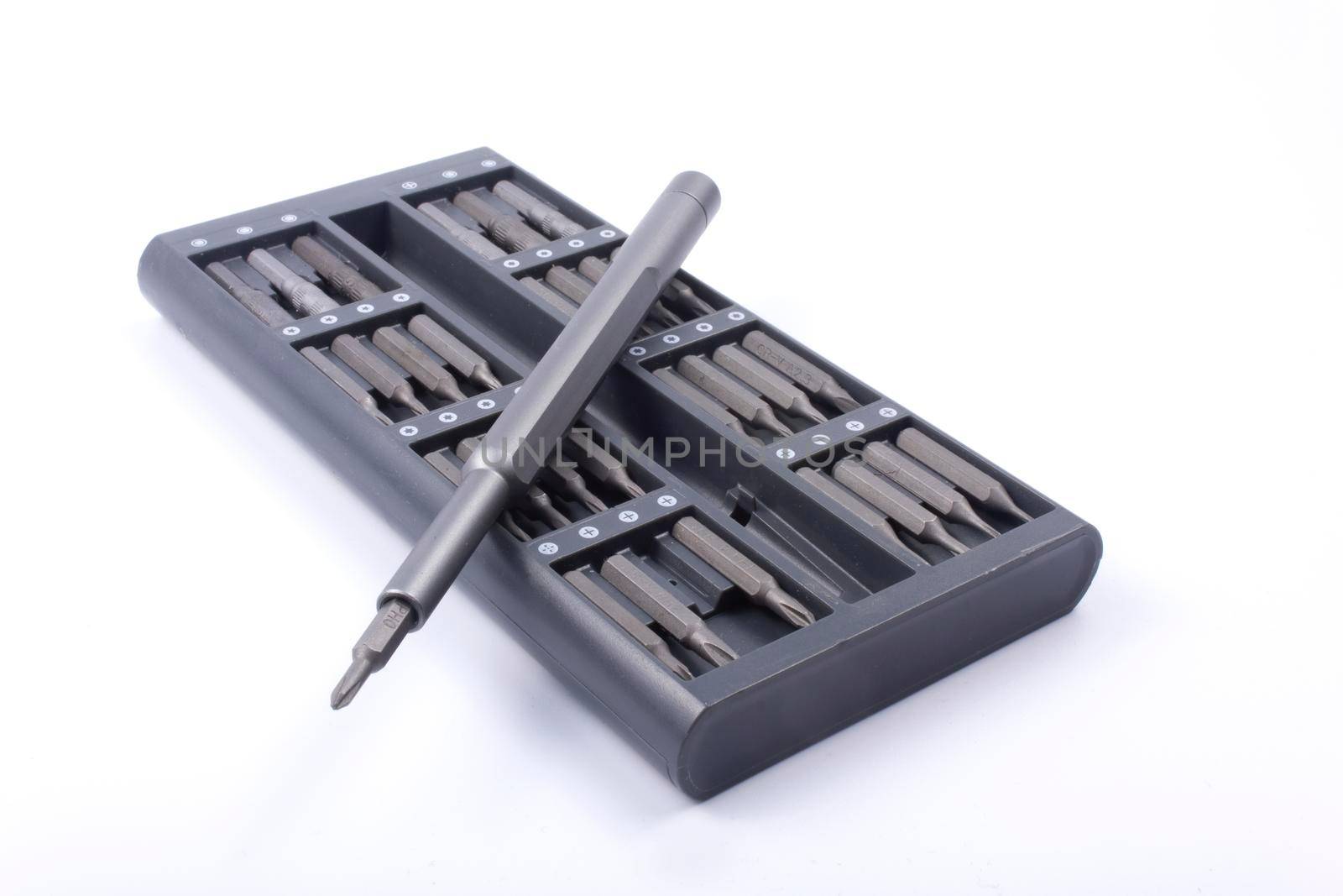 Precision metal, gray screwdriver and a set of interchangeable bits in a dedicated box on a white background
