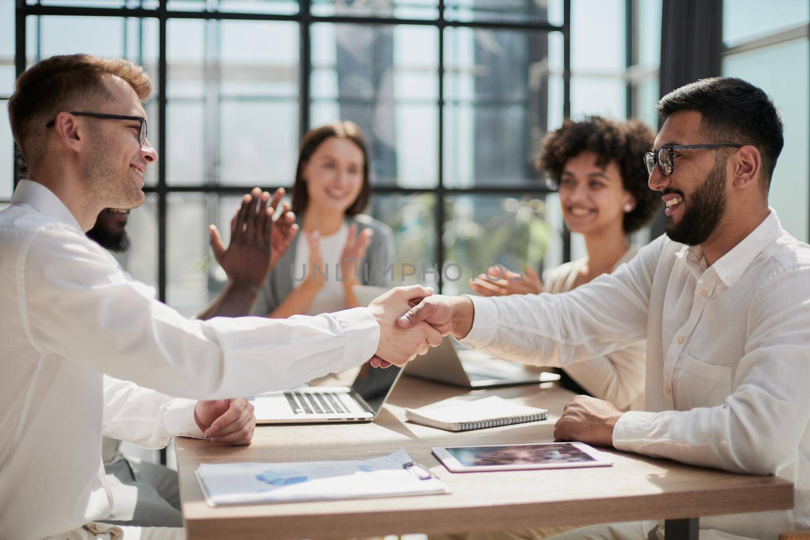 Glad to work with you. Young modern men in smart casual wear shaking hands and smiling while working in the creative office