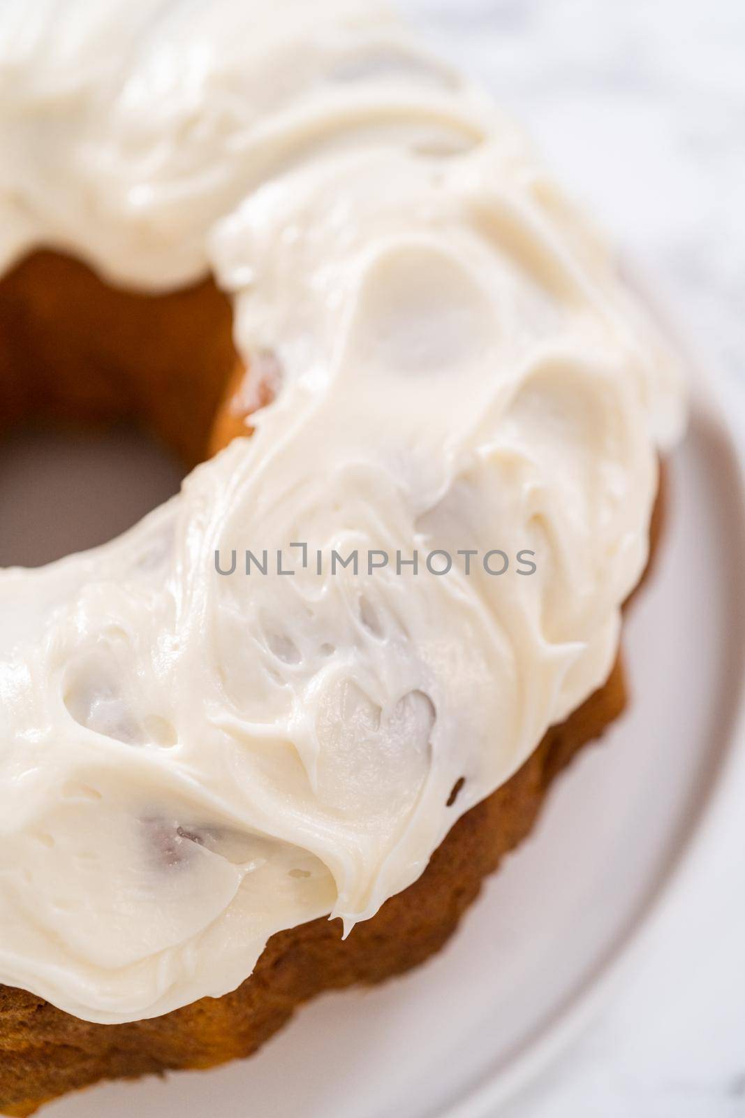 Freshly baked pumpkin bunt cake with cream cheese frosting on the kitchen counter.