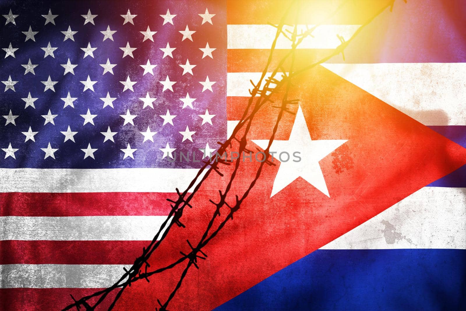Grunge flags of USA and Cuba divided by barb wire sun haze illustration, concept of tense relations between USA and Cuba 