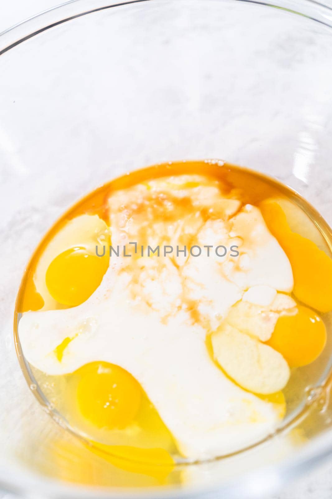 Mixing ingredients in a glass mixing bowl to prepare red velvet bundt cake.