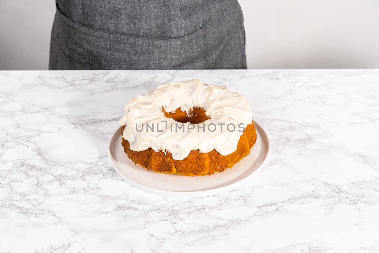 Freshly baked pumpkin bunt cake with cream cheese frosting on the kitchen counter.